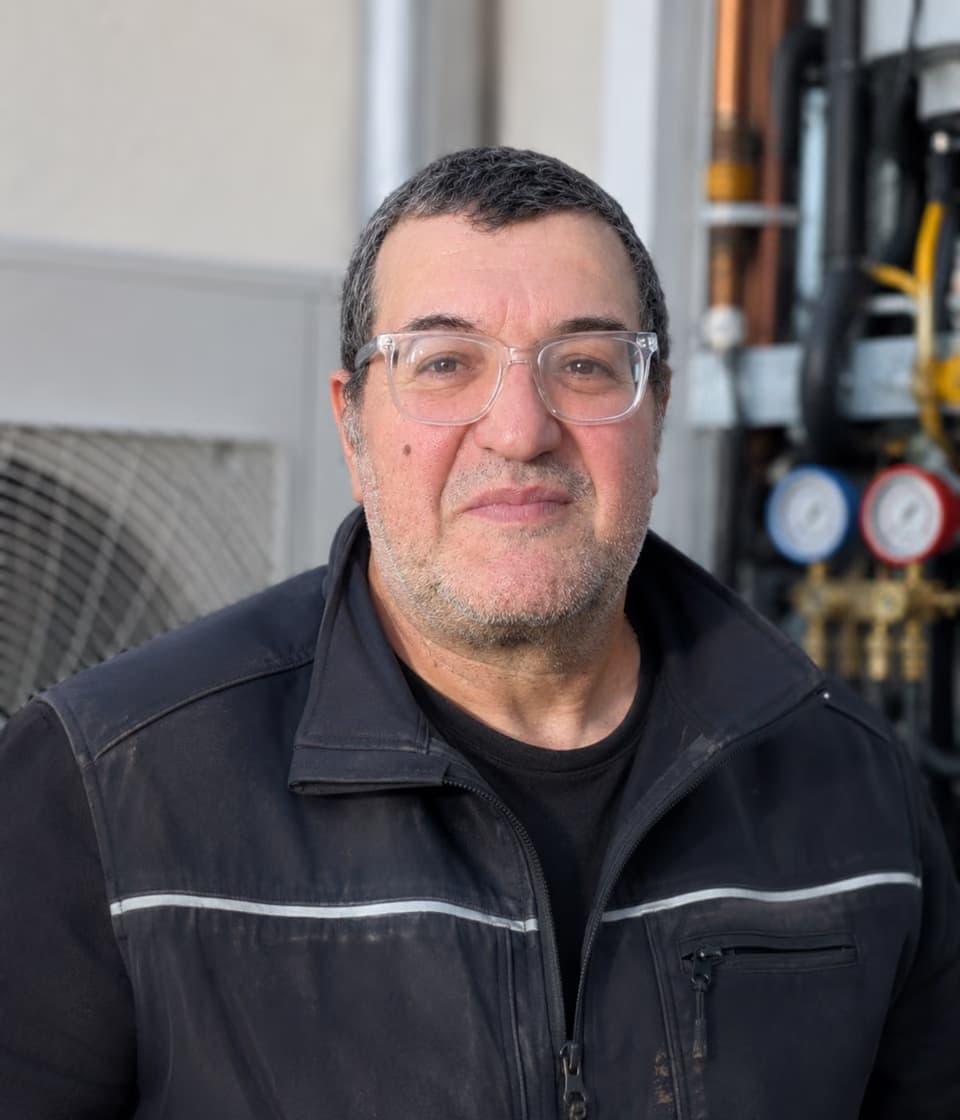 Patrick Perez, artisan frigoriste Climago, devant une pompe à chaleur en Île-de-France